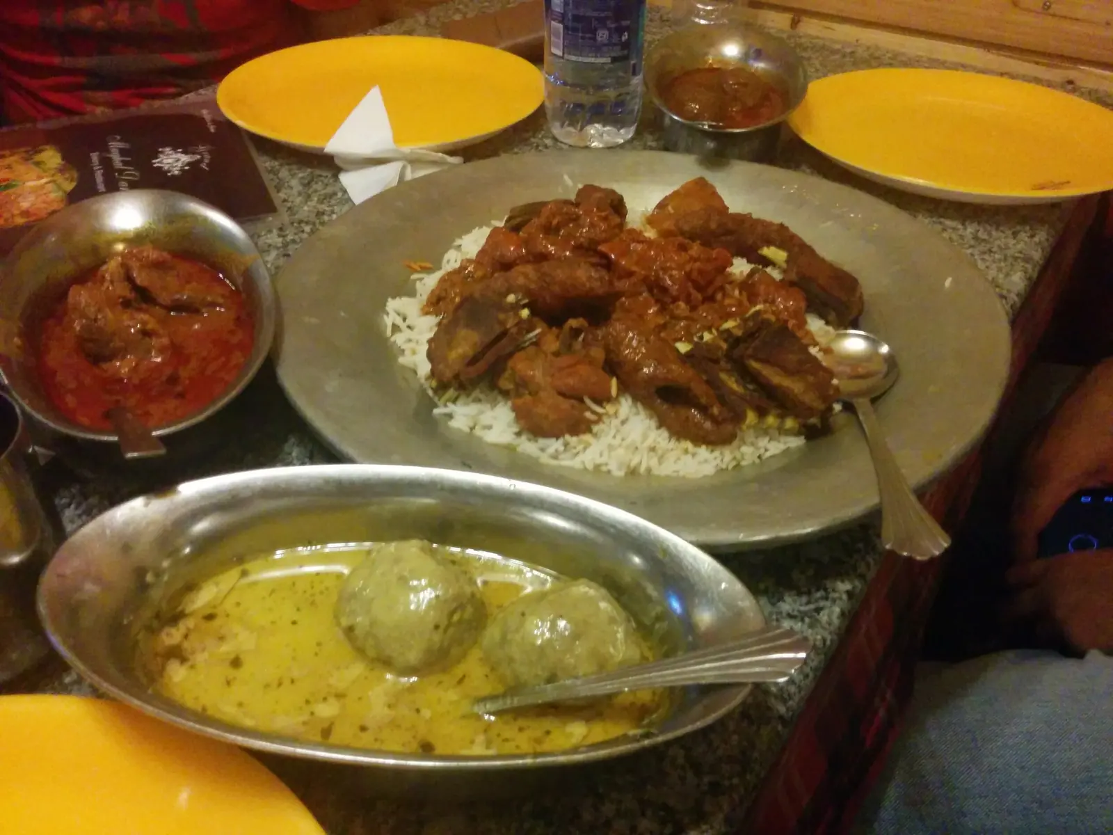 Kashmiri wazwan served in a shared copper trami: rice topped with tabakh maaz and kebabs, with gushtaba and rogan josh