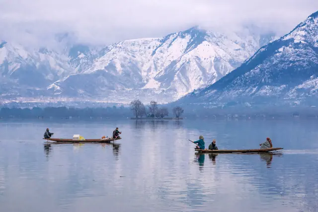 Boats crossing Dal Lake near Char Chinar island, snow-covered Zabarwan mountains rising behind